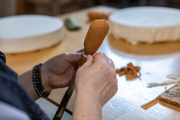 Close up of elderly woman's hands closing a piece of soft leather around the head of a drum stick during a native drum workshop.