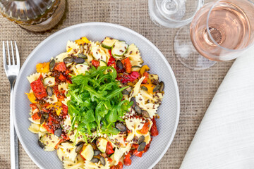 Top view of plate of pasta with rocket and bottle of oil and glass of wine