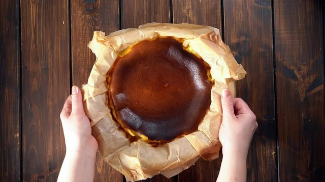 Placing baked basque burnt cheesecake on a rustic table by woman's hands