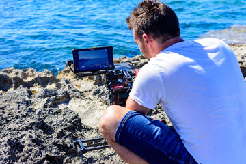 Cámara de cine digital compacta sobre tripode en playa soleada