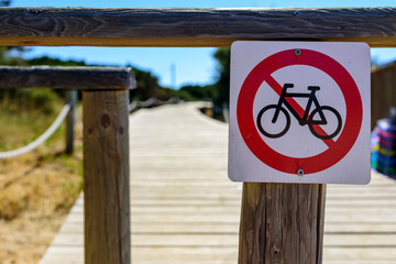 Cartel con señal de prohibición para bicicletas y ciclistas en camino peatonal en playa
