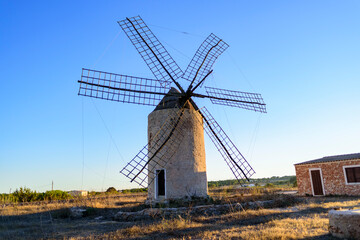 Fototapeta na wymiar Paisaje con antiguo molino ed viento con granero abandonado en campo 
