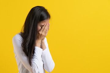 Sad woman cover her face isolated on yellow background