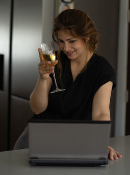 Crying Sad Woman Sitting On A Cabinet In The Kitchen Having An Online Date Holding A Glass Of Champagne