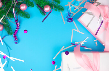 Christmas branch with pink gift boxes and balls on a blue background with confetti. Top view.