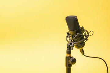 Wired condenser microphone on a stand on a yellow background.