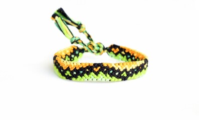 Selective focus of woven DIY friendship bracelet handmade of embroidery bright thread with knots isolated on white background. boho pattern