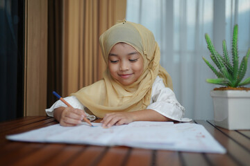 Muslim student child girl writing on the paper book. Asian genius student doing a homework at home. education , study and learning concept. 