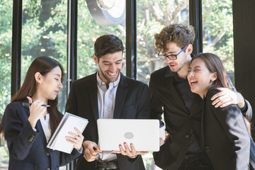 Cheerful,Smiling business people group,teamwork of young asian,caucasian having fun,happy in workplace after project is done,win while conference with partners on laptop.Celebrating success concept.