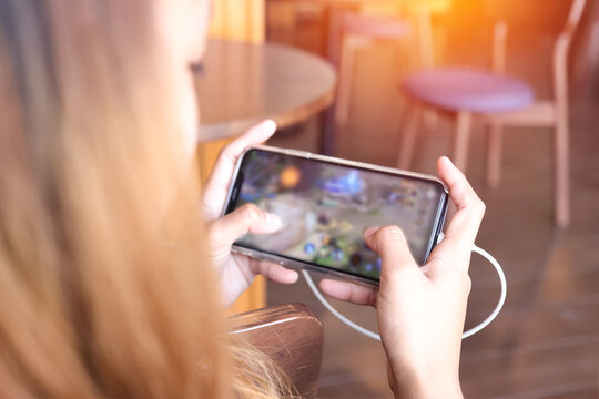 Asian girl are playing the mobile game with blurred on screen at home. The hand is touch screen for play game in the smartphone with clipping path.
