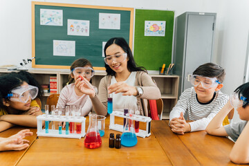Young woman mixing liquids in test tube with multiethnic children watching, learning about science,...