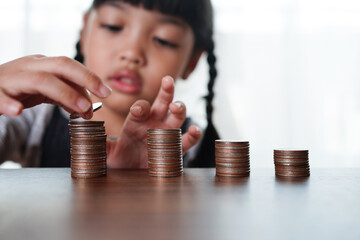 Hand of Little child girl putting coins to stack of coin step growing growth saving money, Concept...