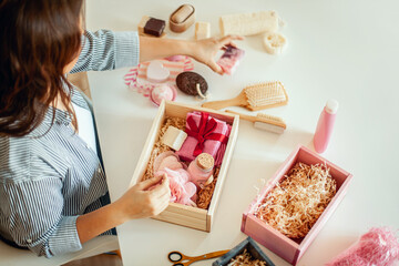 Naklejka na ściany i meble Young woman placing handmade organic bath supplies into bridesmaid gift box set.