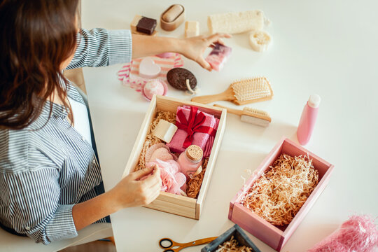 Young Woman Placing Handmade Organic Bath Supplies Into Bridesmaid Gift Box Set.