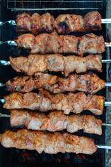 pork kebab on skewers is grilled over charcoal, smoke over a barbecue, the last degree of cooking, close