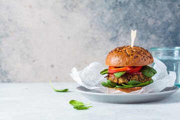 Vegan lentil burger with baked sweet potato, tomato sauce and fresh vegetables on gray plate, copy...