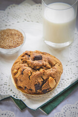 Close up high angle view chocolate chip cookies on a white table with a cup of milk in brown sugar background