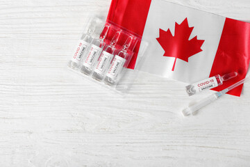 Vaccine for immunization against COVID-19 and flag of Canada on white wooden background