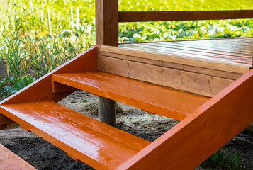 A staircase with wooden steps painted oil brown on a background of green grass. New staircase...