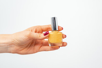 Female hand holding nail polish against white background