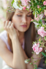 Outdoor photo of a beautiful young woman surrounded by flowers. Spring Flower. Portrait of a girl with roses. High quality photo.