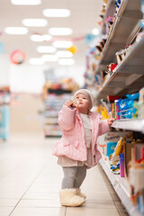 Family shopping. A cute little child stands near the shelf with products, and holds a candy in his hands. The concept of shopping and consumerism