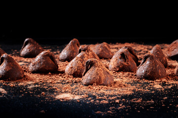Chocolate truffles, side view on a black background