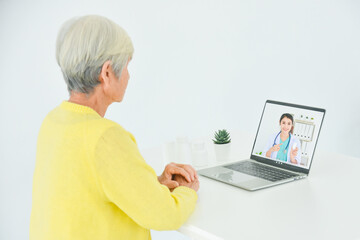 Senior woman sitting in front of laptop computer making video call chat with doctor. Telemedicine concept. - obrazy, fototapety, plakaty