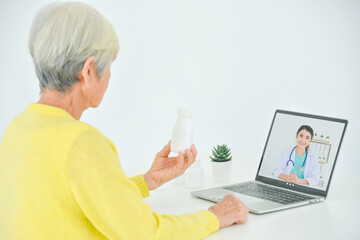 Senior woman sitting in front of laptop computer making video call chat with doctor. Telemedicine concept. - obrazy, fototapety, plakaty