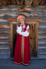 Portrait of girl in russian authentic red clothes on wooden background