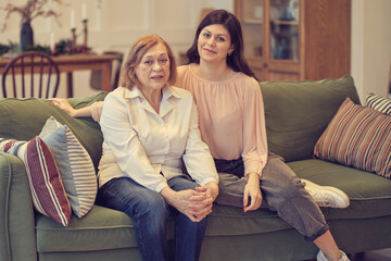 Obraz premium granddaughter and senior grandmother having fun enjoying talk sit on sofa, bonding chatting relaxing at home together. two different generation relative people