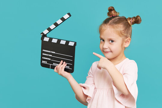 Funny Smiling Child Girl Hold Film Making Clapperboard Isolated On Blue Background. Little Clipmaker, Acting Training. Funny Face. Copy Space For Text..