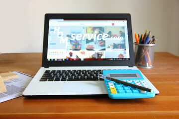 laptop on wood table is opening home service .com home page serving all matters concerning the home