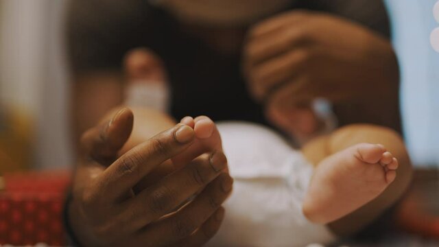 African american father playing with baby feet. Close up slow motion. High quality 4k footage