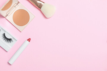 Decorative cosmetics on a pink background. Compact Powder Makeup Brush False Eyelashes Lipstick. Copy space flat lay top view.