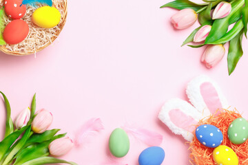 Naklejka na ściany i meble Easter eggs in a nest and in a basket, bunny ears, tulips and copy space on a pink background. Top view flat lay greeting card.