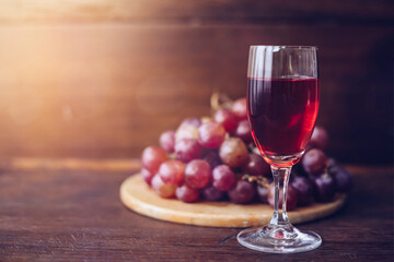 Close-up of a wine glasses with bread in communion plate  against window light with bokeh on wooden table, Christian background with copy space