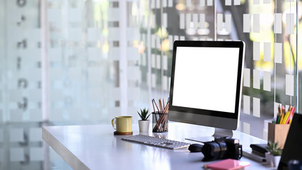 Mock up computer with white screen, camera and office supplies on photographer workstation.