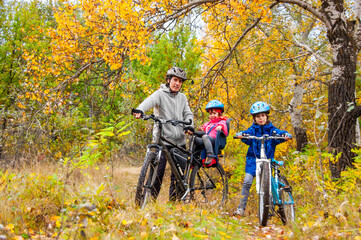 Plakat Family cycling in golden autumn park, active father and kids ride bikes, family sport and fitness with children outdoors 