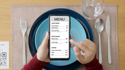 Hand's customer scan QR code for online menu service at table in restaurant during pandemic...