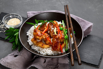 Chicken baked in sauce served with rice and vegetables on gray background.
