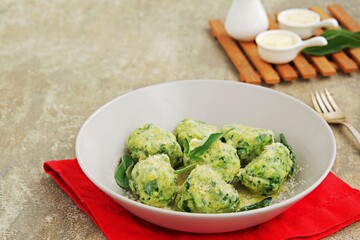 Ricotta and spinach gnocchi or dumplings with parmesan cheese and sage butter in a gray plate on a concrete background. Spinach recipes.