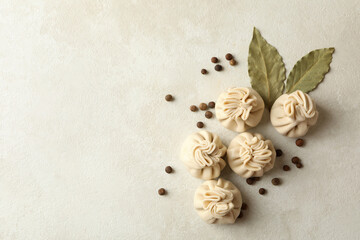Raw khinkali, pepper and bay leaves on white textured background