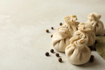 Raw khinkali, pepper and bay leaves on white textured background