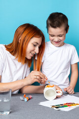 happy family mother and child painting together at home on blue background.  Children's creativity.