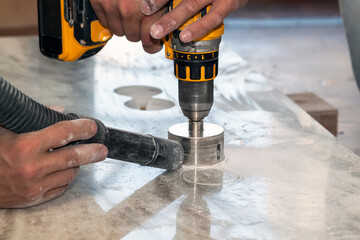 handyman cut round holes for electrical outlets in marble countertop for the kitchen using hand...