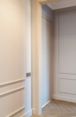 Close up view of modern and bright interior of empty cream colored corridor with herringbone parquet floor