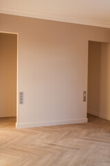 Modern and bright interior of empty cream-colored room with herringbone parquet floor