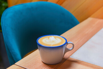 Coffee cup with coffee foam on wooden table. Latte coffee in restaurant or cafe, eating out concept, coffee concept.