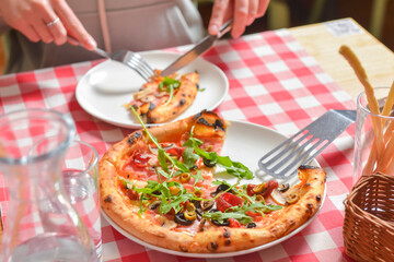 Supreme pizza on a white plate over red plaid tablecloth. Italian cuisine, Italian concept.